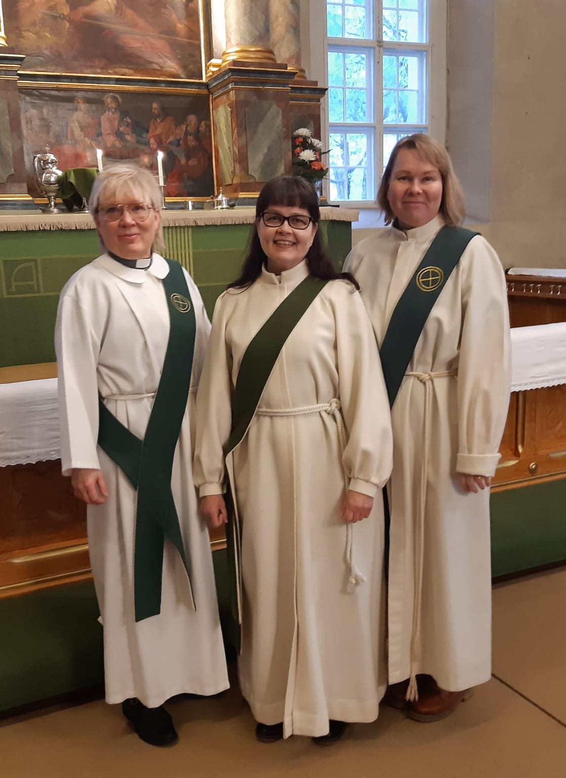 Diakonit Hannele Airola, Marika Hietanen ja Johanna Penkkimäki seisovat Paimion kirkon alttarin edustalla.